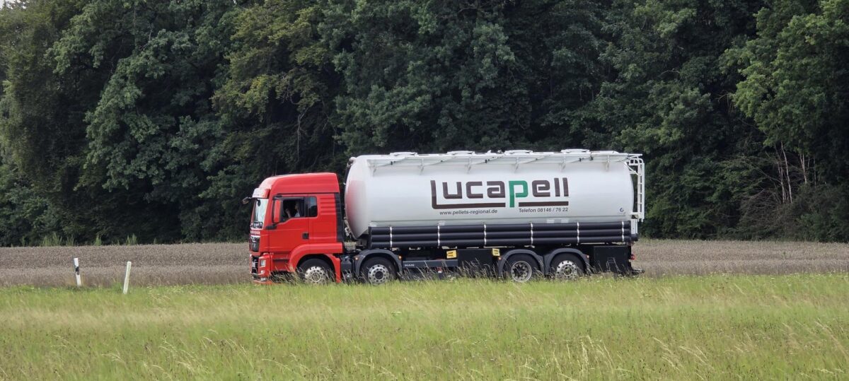 Lucapell-Silolkw mit rotem Fahrerhaus und weißem Silo vor einem Waldrand